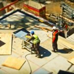 Construction workers engaging in tasks at an outdoor building site with safety hats and equipment.